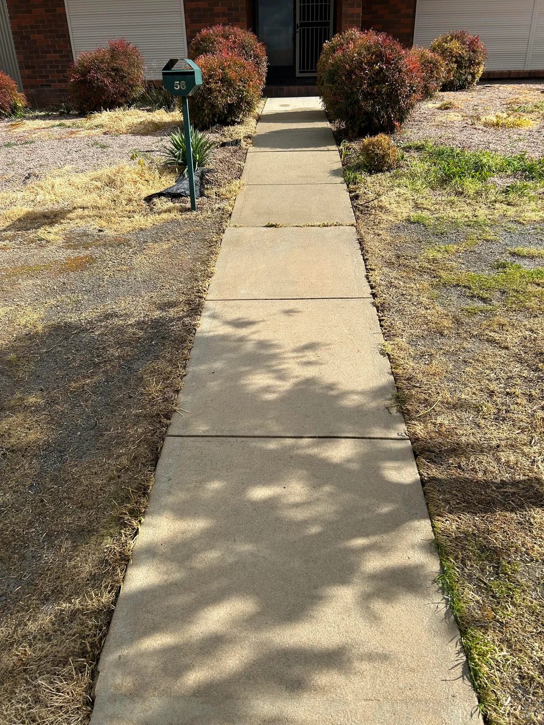 The same sidewalk restored to bright, even concrete after pressure washing