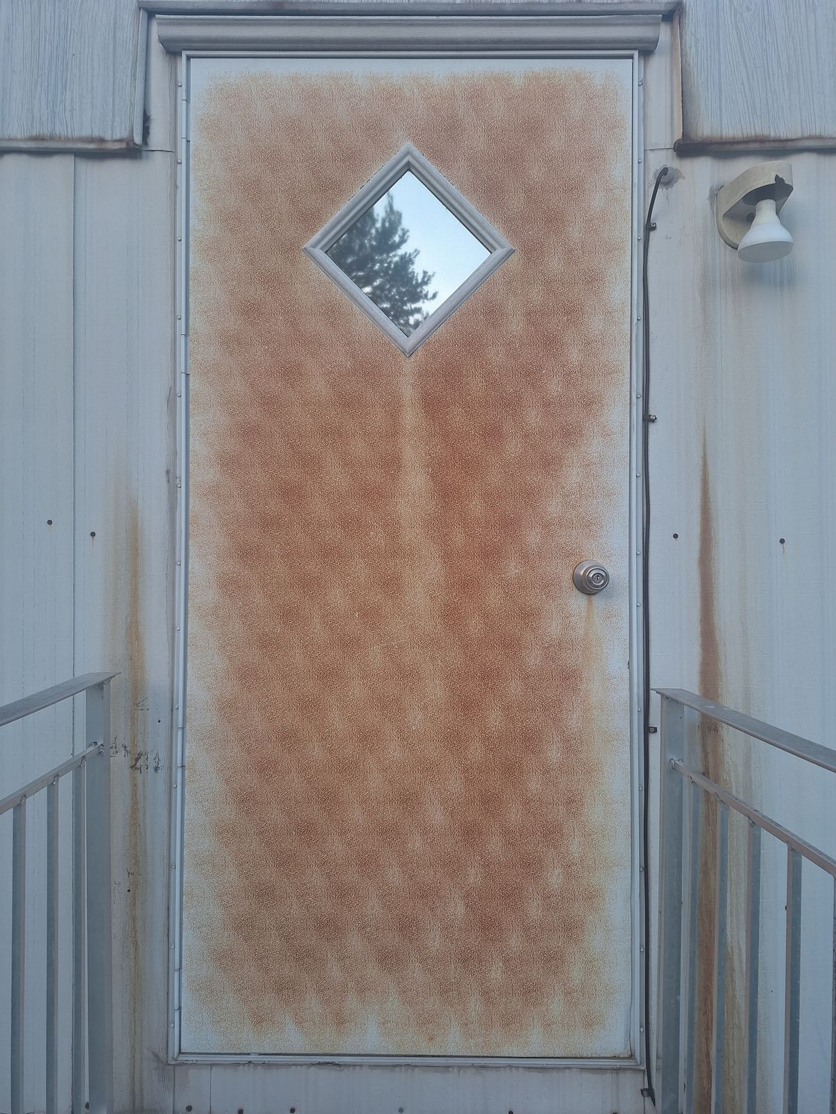Steel entry door covered in heavy orange rust staining, before rust removal